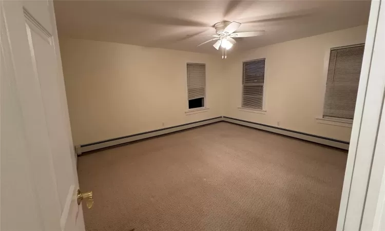 Carpeted empty room featuring ceiling fan