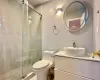 Bathroom featuring vanity, toilet, and a shower with door