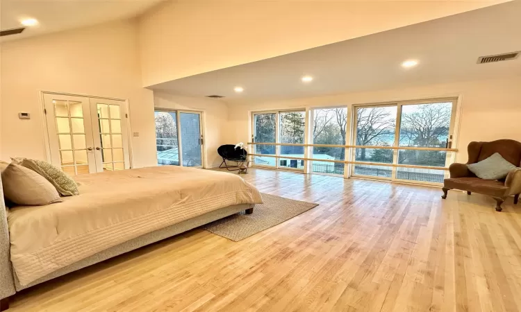 Bedroom featuring high vaulted ceiling, light wood-type flooring, access to outside, and french doors