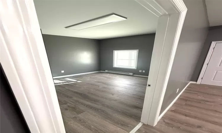 Unfurnished room featuring hardwood / wood-style floors and a baseboard radiator