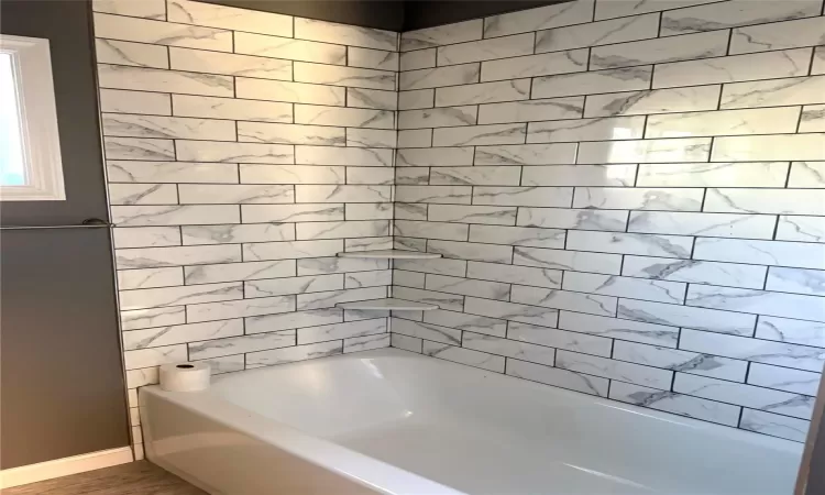 Bathroom with hardwood / wood-style floors and tiled shower / bath