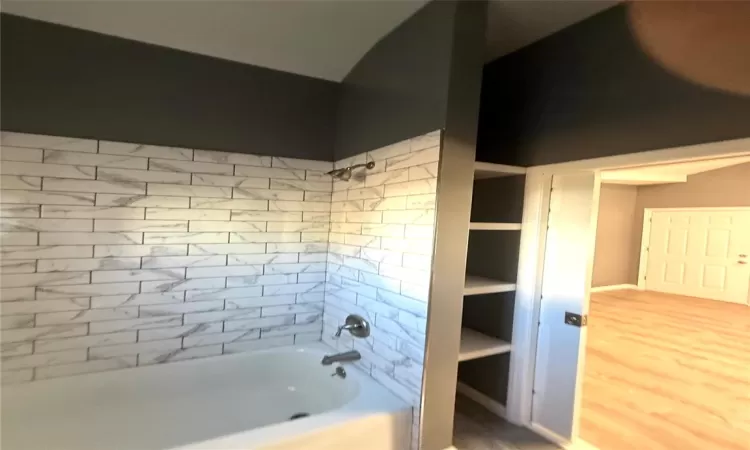 Bathroom featuring hardwood / wood-style floors, built in features, and tiled shower / bath