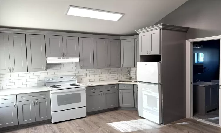 Kitchen featuring white appliances, light hardwood / wood-style flooring, and gray cabinetry