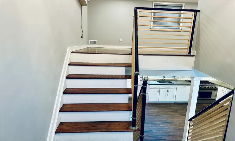 Staircase featuring hardwood / wood-style floors and sink