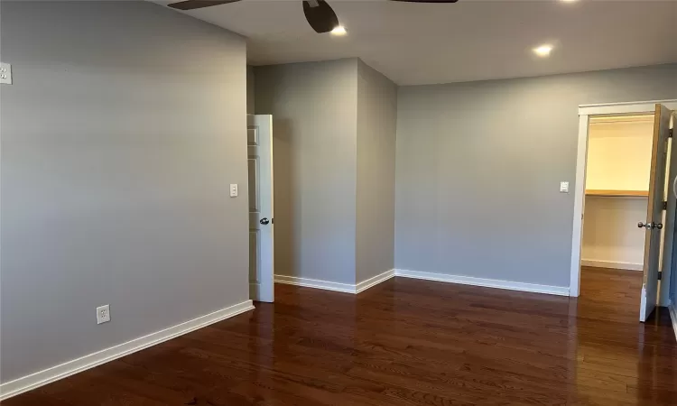 Primary bedroom with hardwood flooring and walk in closet