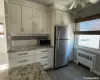 Kitchen with backsplash, stainless steel refrigerator, light stone counters, and radiator