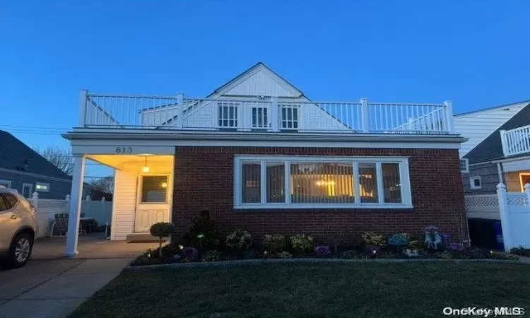 View of front of property with a lawn and a balcony