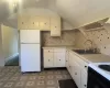 Kitchen featuring white cabinetry, sink, backsplash, white fridge, and vaulted ceiling