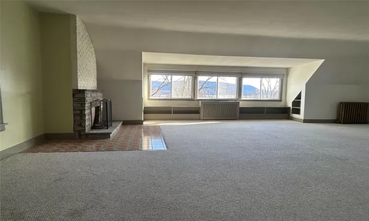 Unfurnished living room with carpet flooring, a fireplace, and a wealth of natural light