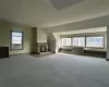 Unfurnished living room featuring carpet, lofted ceiling, radiator heating unit, and a fireplace