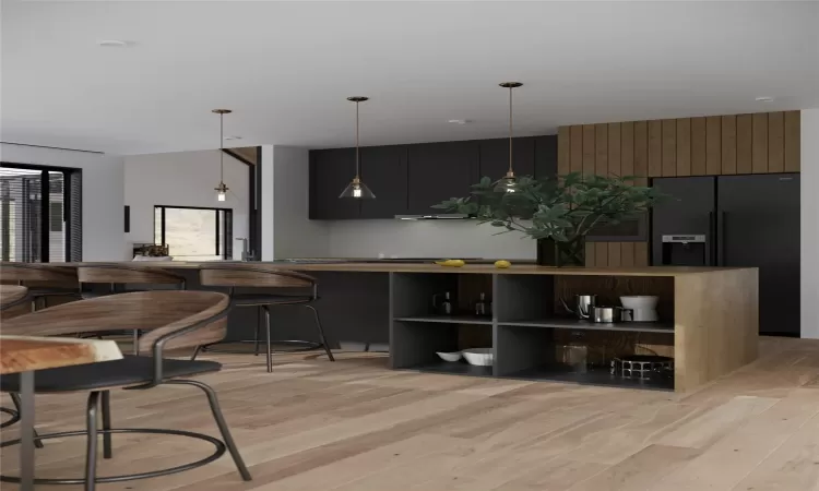 Kitchen with hanging light fixtures, kitchen peninsula, a kitchen bar, black fridge with ice dispenser, and light wood-type flooring