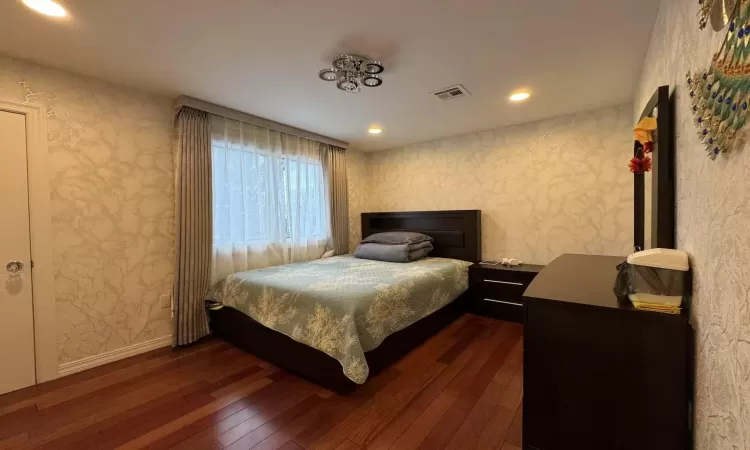 Bedroom with dark hardwood / wood-style flooring