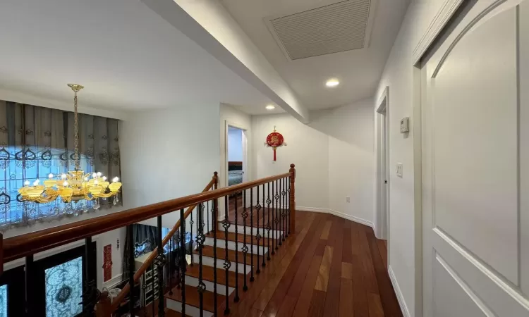 Corridor with dark hardwood / wood-style flooring and an inviting chandelier