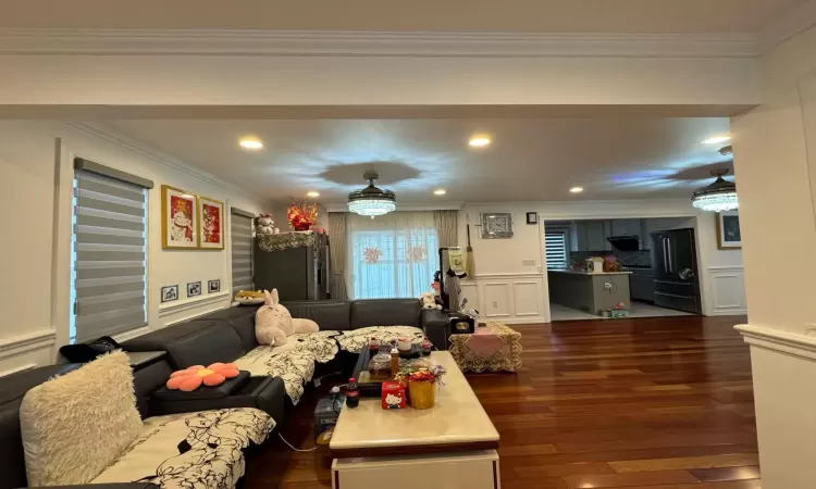 Living room featuring dark hardwood / wood-style flooring, ceiling fan, and ornamental molding