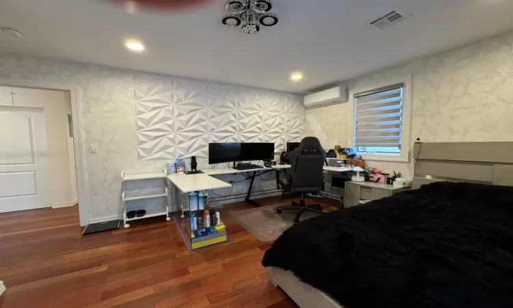 Bedroom featuring a wall mounted AC and dark hardwood / wood-style floors