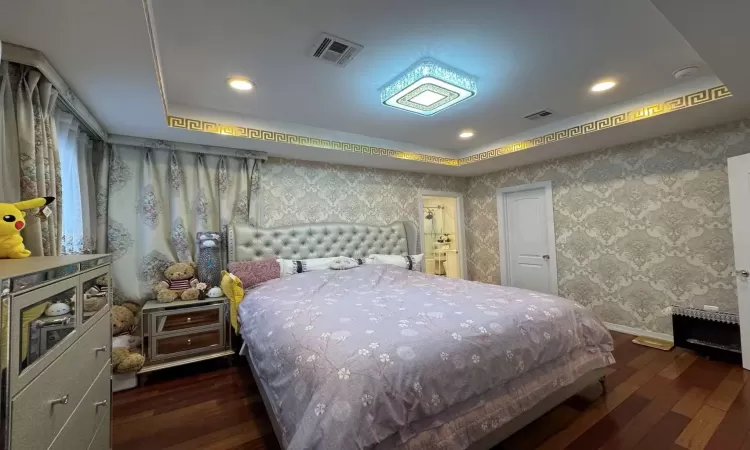 Bedroom featuring a raised ceiling and dark wood-type flooring