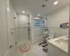 Full bathroom featuring combined bath / shower with glass door, vanity, toilet, and tile walls