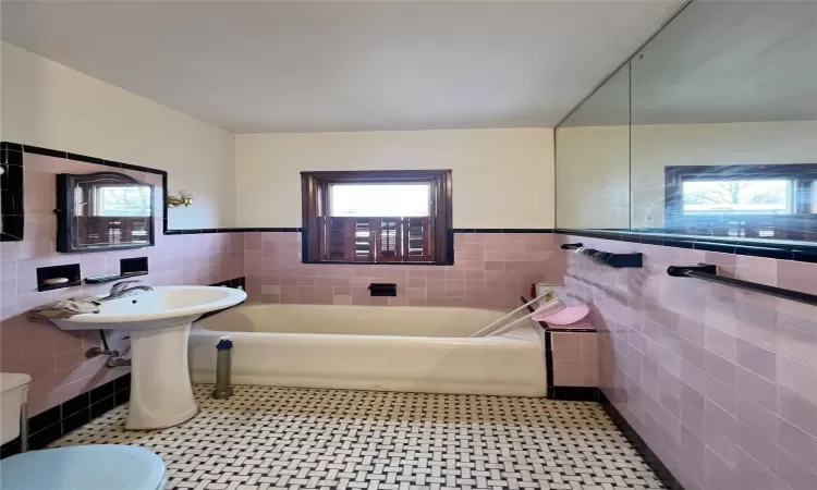 Bathroom with tile walls, tile patterned floors, and a bathing tub