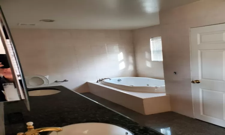 Bathroom featuring tiled bath, sink, and tile walls