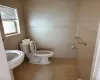 Bathroom with tile patterned flooring, toilet, and tile walls