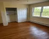 Unfurnished bedroom with dark hardwood / wood-style floors, a closet, and a baseboard radiator