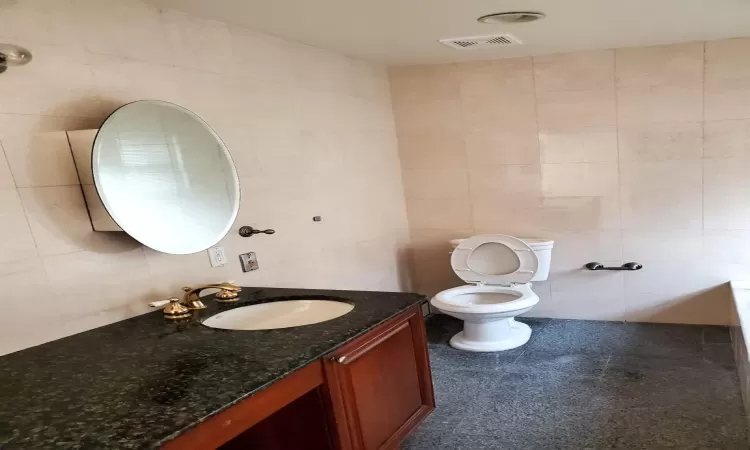 Bathroom with vanity, tile walls, and toilet