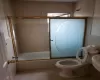 Bathroom featuring tile patterned flooring, enclosed tub / shower combo, and toilet