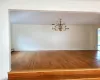 Unfurnished dining area with hardwood / wood-style floors, a notable chandelier, and a baseboard radiator