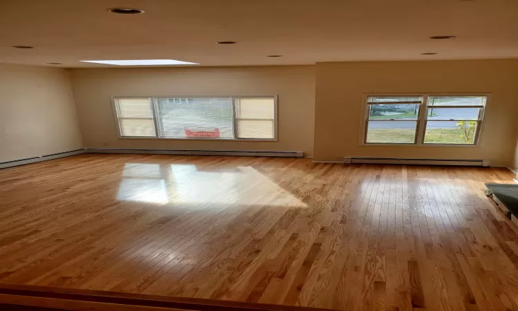 Unfurnished room featuring light wood-type flooring and baseboard heating