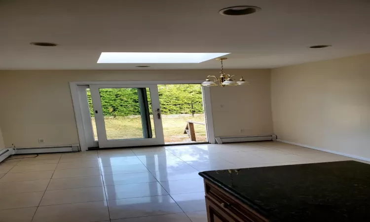 Unfurnished room featuring light tile patterned floors, a skylight, and baseboard heating