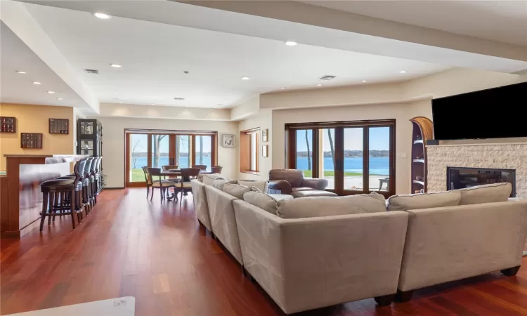 Living room with dark hardwood / wood-style floors and a stone fireplace