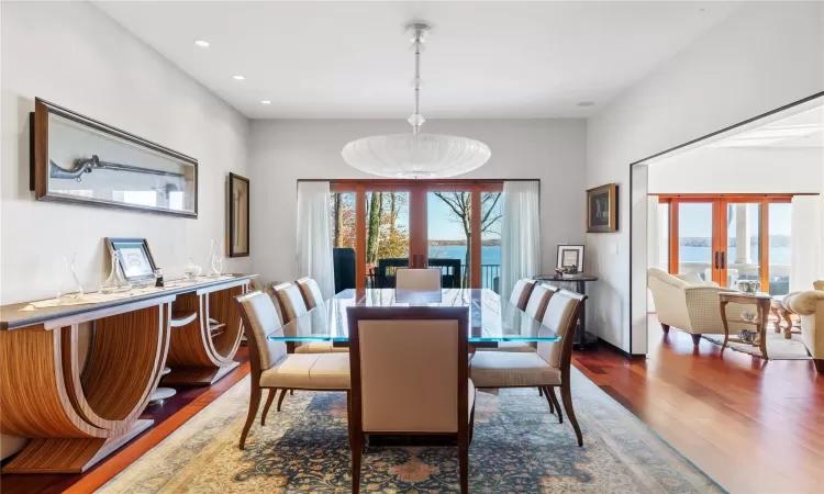 Dining area with a healthy amount of sunlight, french doors, a water view, and wood-type flooring