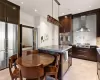 Kitchen with wall chimney range hood, tasteful backsplash, a kitchen island, dark brown cabinetry, and stainless steel appliances