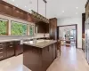 Kitchen with a center island, a kitchen breakfast bar, sink, decorative light fixtures, and dark brown cabinets