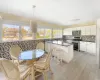 Kitchen featuring backsplash, decorative light fixtures, a kitchen bar, white cabinets, and appliances with stainless steel finishes