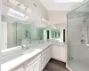 Bathroom with hardwood / wood-style floors, vanity, lofted ceiling with skylight, and walk in shower