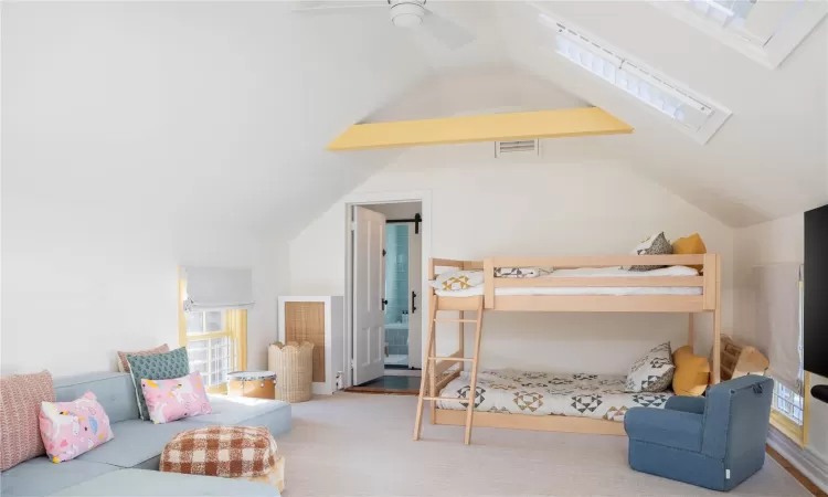 Bedroom featuring vaulted ceiling with skylight, ceiling fan