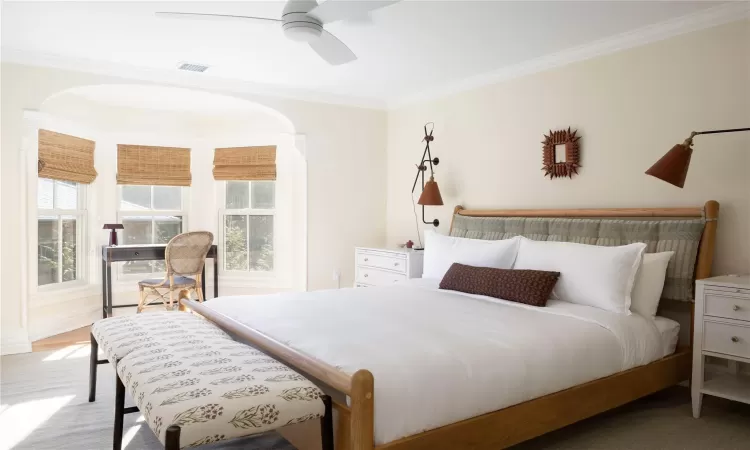 Bedroom with multiple windows ceiling fan, and ornamental molding