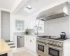 Kitchen featuring white cabinetry, sink, stainless steel appliances, wall chimney range hood, and backsplash