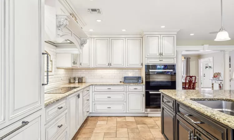 Kitchen featuring a center island, a kitchen breakfast bar, light stone counters, pendant lighting, and vaulted ceiling