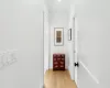 Hallway with light wood-type flooring and ornamental molding