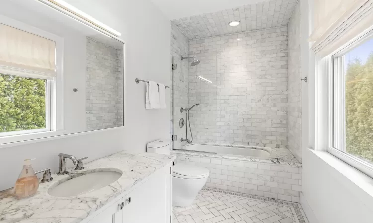 Full bathroom with tile patterned flooring, vanity, toilet, and tiled shower / bath combo