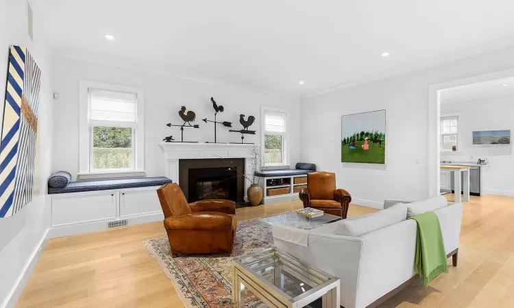 Living room with plenty of natural light, ornamental molding, and light hardwood / wood-style flooring