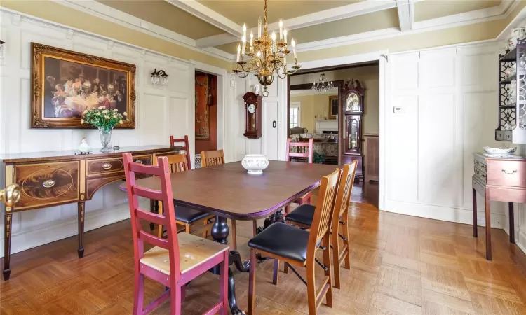 Dining space with a notable chandelier, beam ceiling, and parquet floors