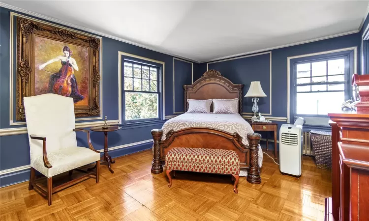 Bedroom featuring light parquet floors, multiple windows, and ornamental molding