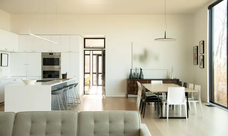 Dining area with a wall of windows and light wood-type flooring