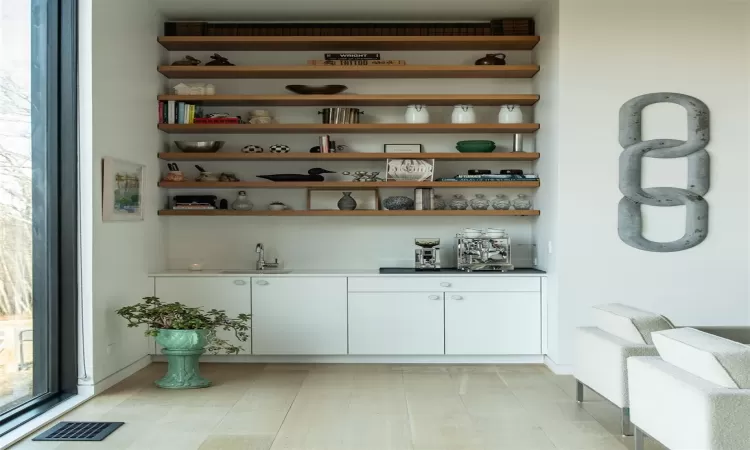 Bar with white cabinetry, sink, and light wood-type flooring