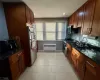 Kitchen with light tile patterned flooring, radiator heating unit, appliances with stainless steel finishes, and dark stone counters