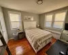 Bedroom featuring dark wood-type flooring, radiator, and multiple windows