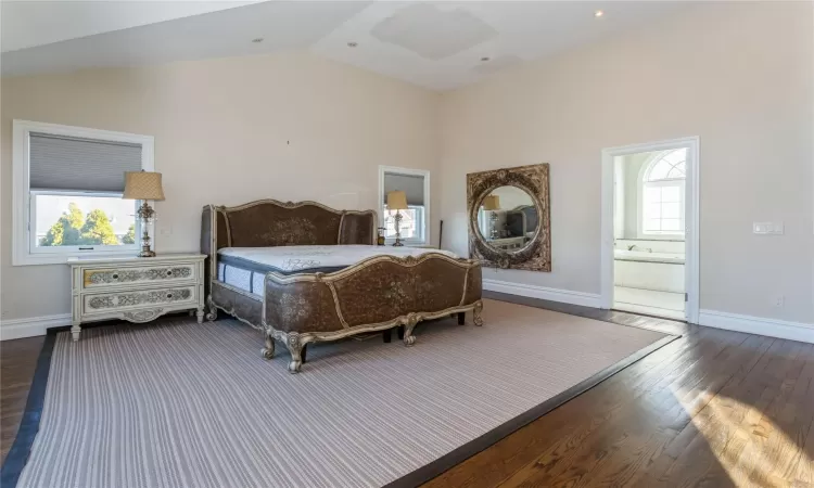 Bedroom featuring vaulted ceiling, dark hardwood / wood-style flooring, and ensuite bath